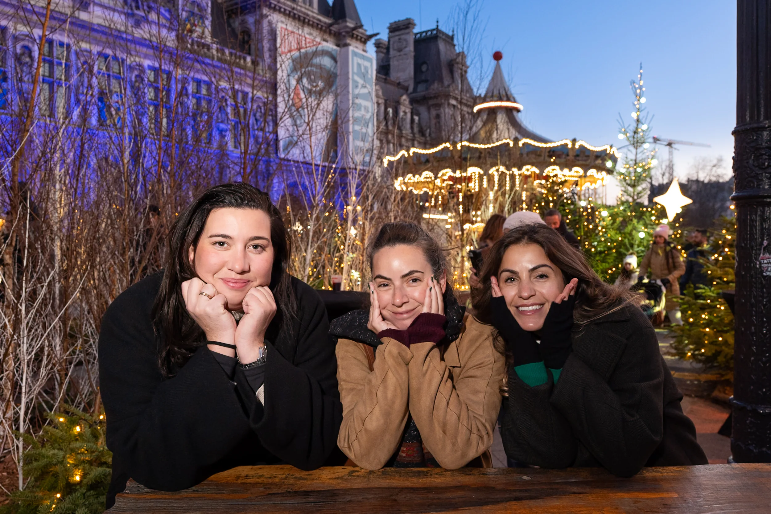 Three friends sharing a portrait beneath the Christmas lights and carousel in Paris