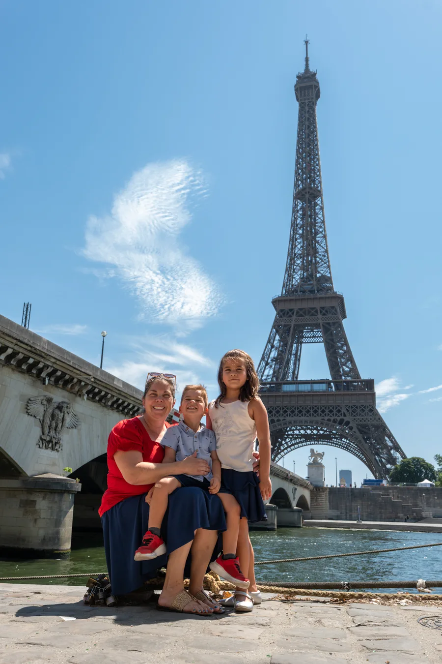 Family portrait beside the Seine with the Eiffel Tower behind them