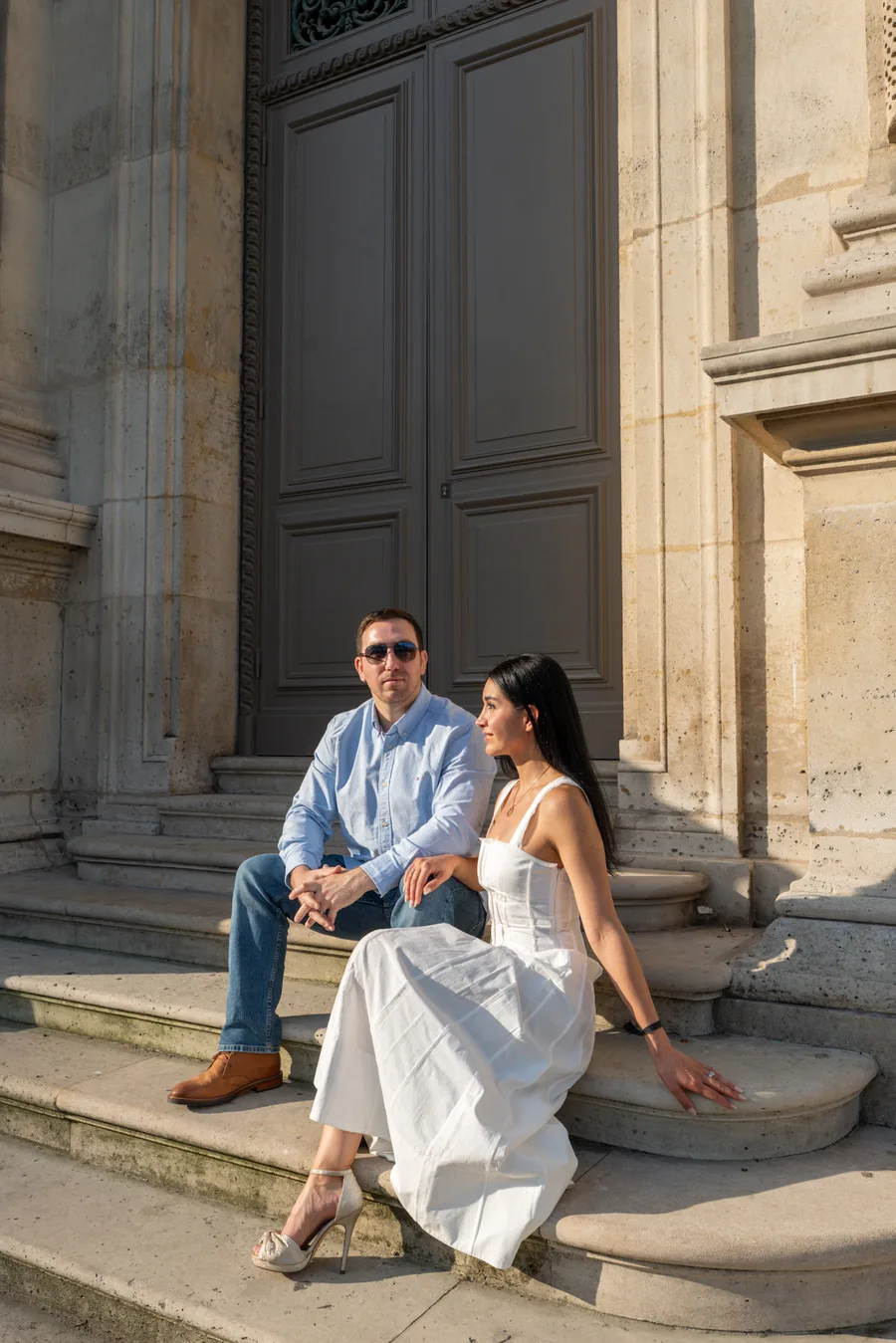 Couple seated on the steps of a historic Parisian building