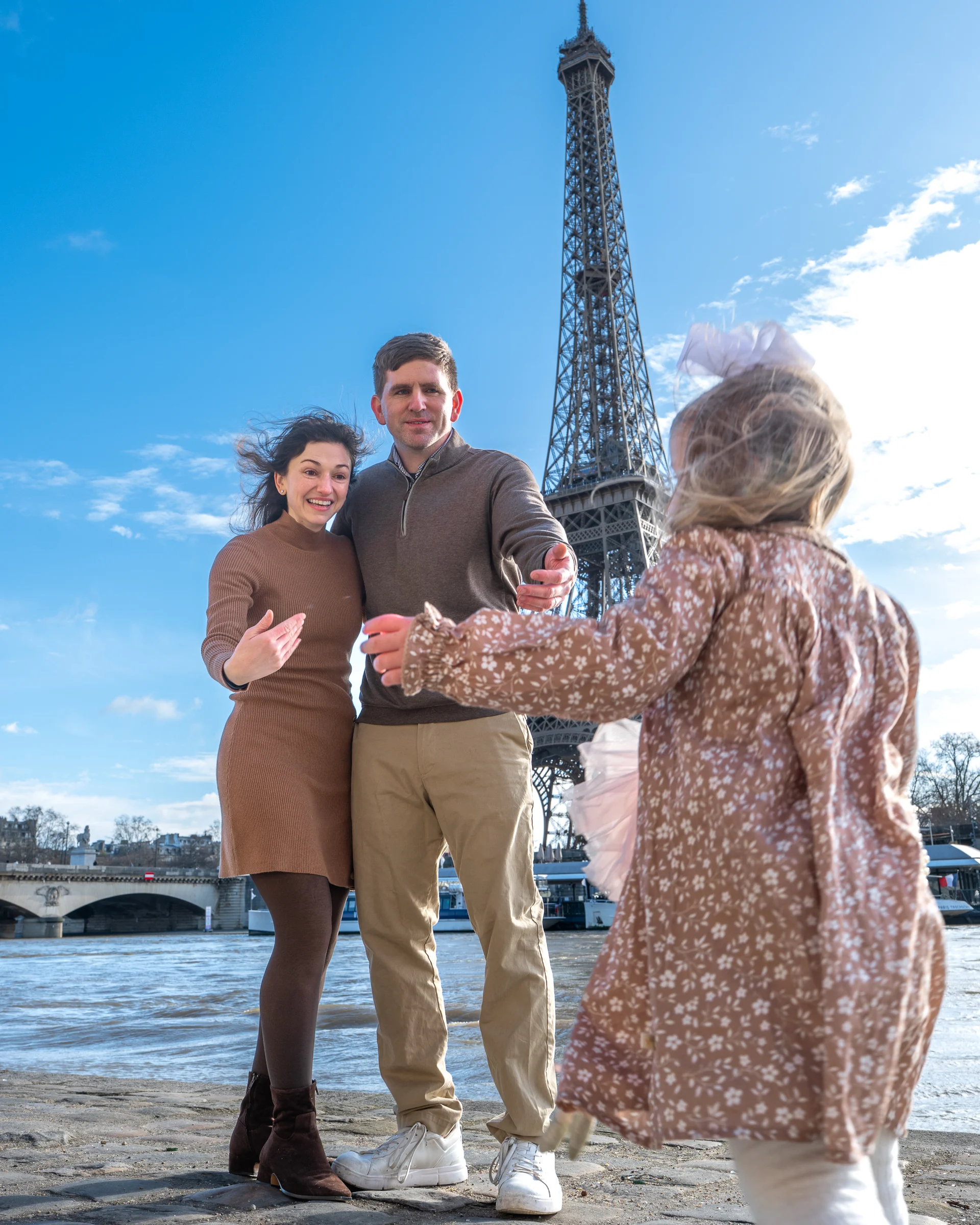 Family with child running toward parents, Eiffel Tower behind