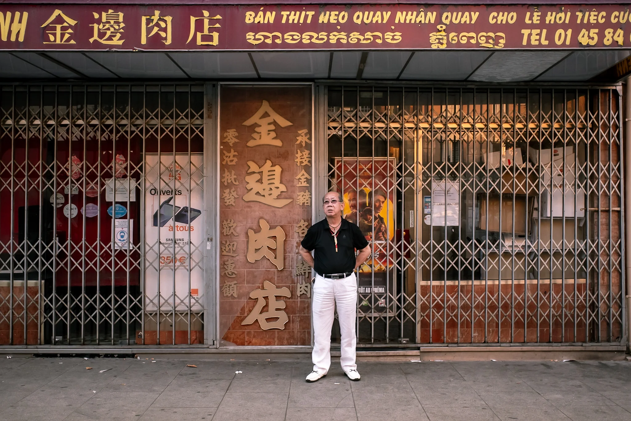 A man standing in front of a shuttered Asian grocery store in Paris &mdash; photograph by Dan Umareta